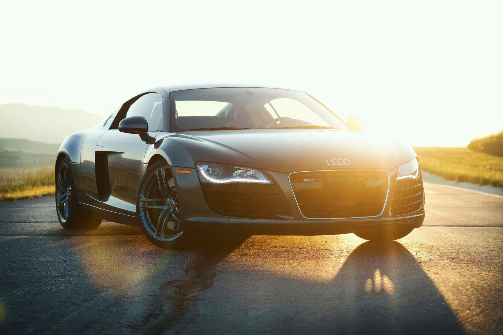 An Audi sportscar with the sun setting behind it