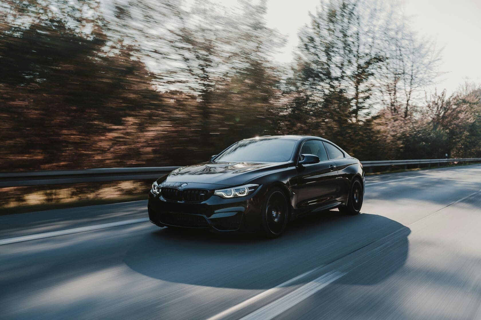 A black BMW sedan driving on a rural road