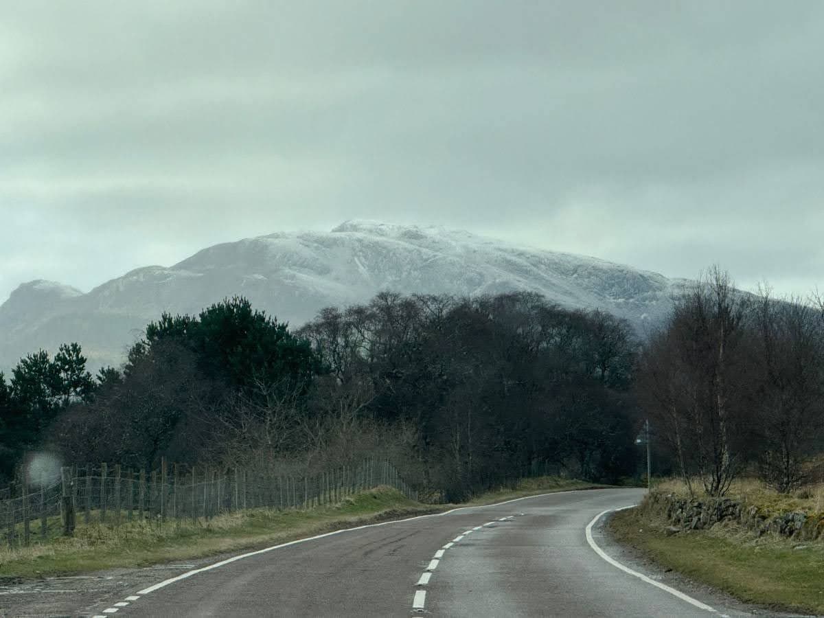 A rural road in Scotland with a foggy mountain in the background