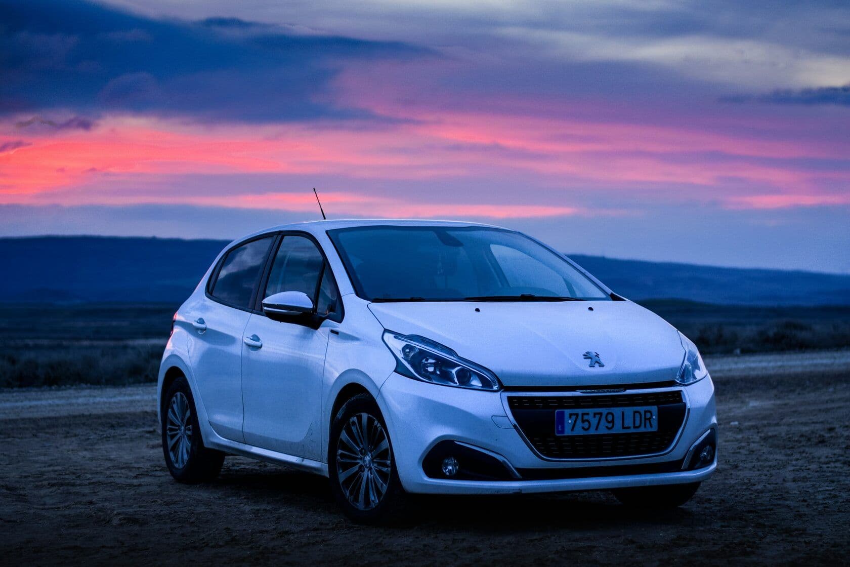 A white Peugeot parked at dusk