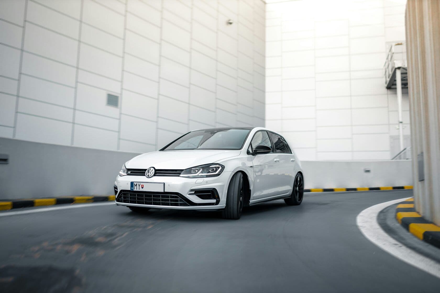 A white VW car exiting a parking garage
