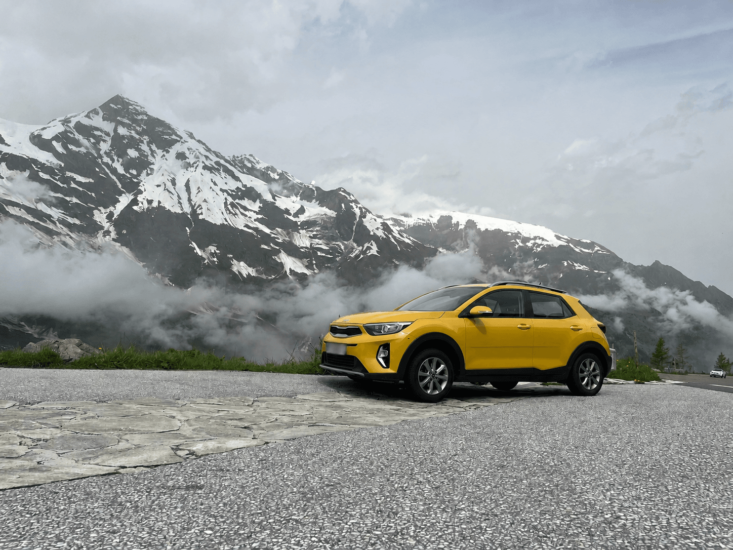 Yellow car on the side of the road with snowy mountain in the background